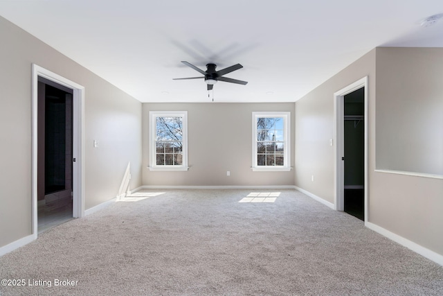 unfurnished bedroom with a spacious closet, a ceiling fan, baseboards, and carpet floors