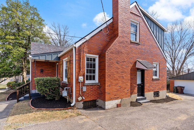 view of home's exterior featuring brick siding, entry steps, a chimney, and an outdoor structure