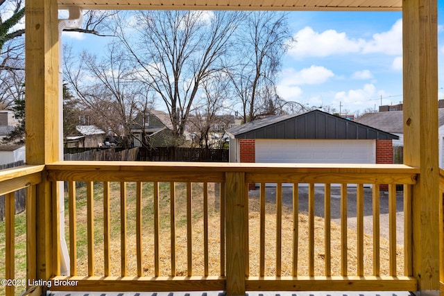 wooden deck featuring a detached garage, an outdoor structure, and fence