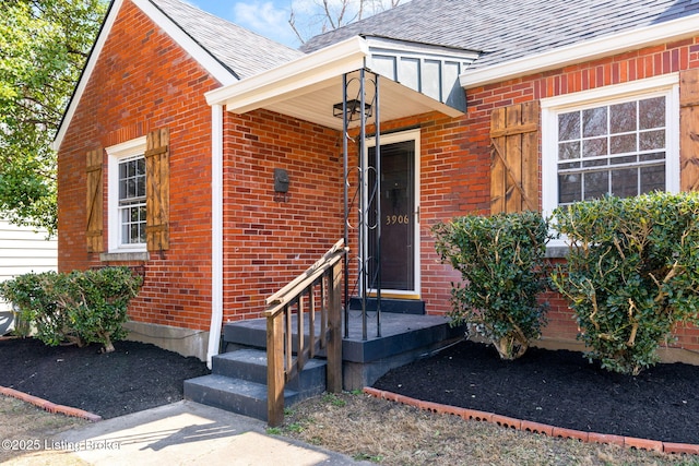 entrance to property with brick siding and a shingled roof