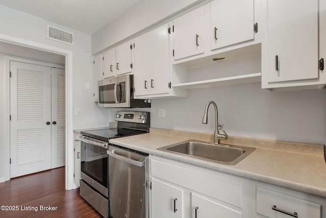 kitchen with a sink, light countertops, white cabinets, stainless steel appliances, and open shelves