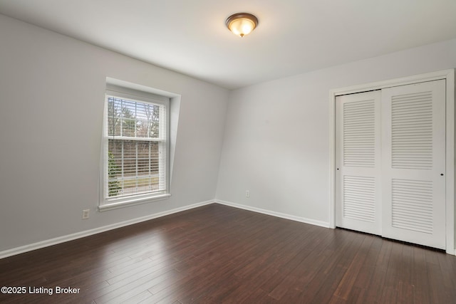 unfurnished bedroom featuring dark wood-type flooring, baseboards, and a closet