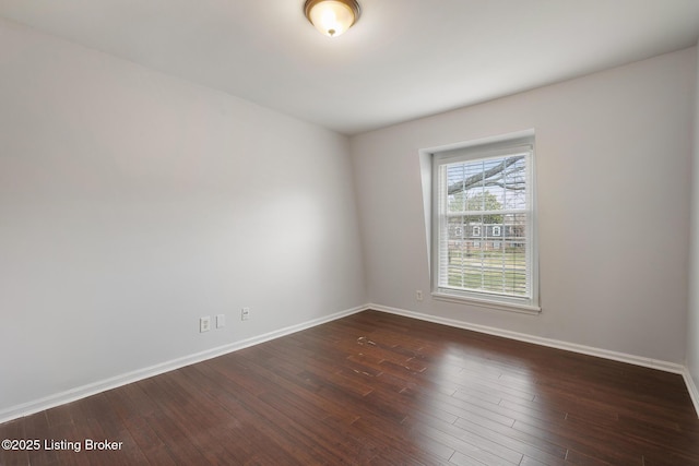 empty room featuring dark wood-type flooring and baseboards