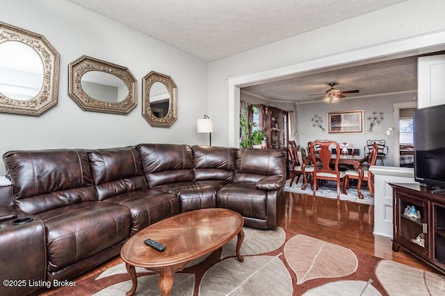 living room with a textured ceiling, a ceiling fan, and wood finished floors