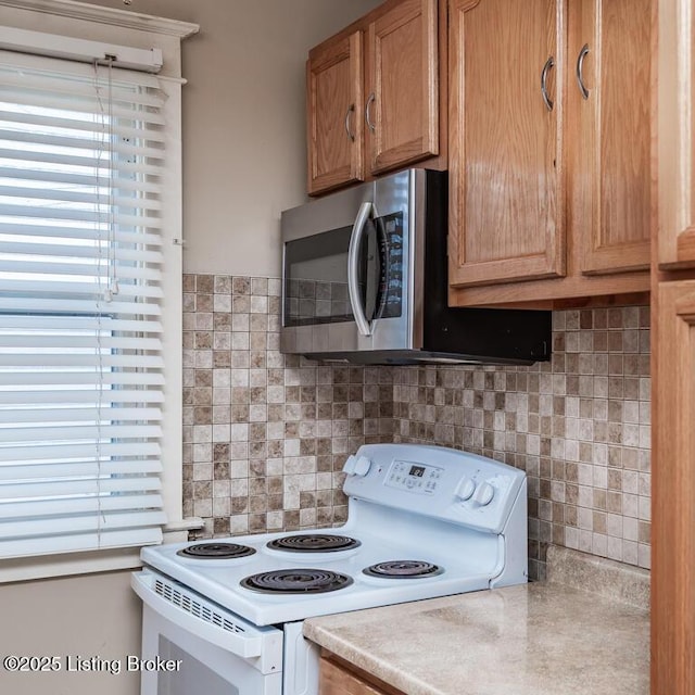 kitchen featuring tasteful backsplash, stainless steel microwave, white electric stove, and light countertops