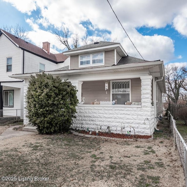 view of front of property with covered porch, fence private yard, and roof with shingles