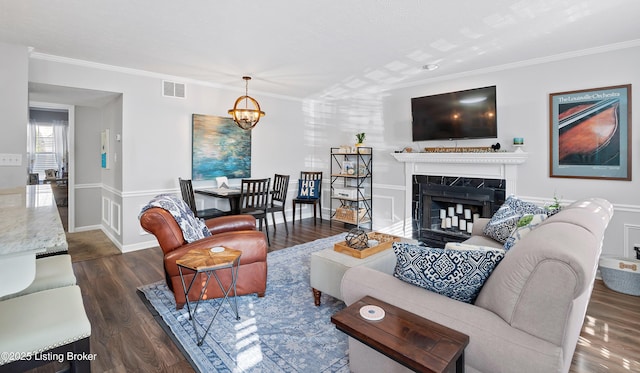 living area with visible vents, an inviting chandelier, dark wood finished floors, and ornamental molding