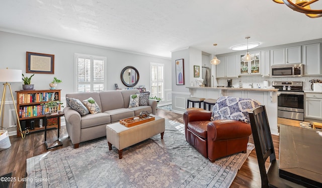 living room featuring dark wood finished floors, crown molding, a decorative wall, and a textured ceiling