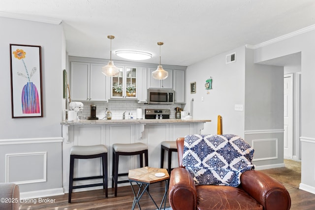 kitchen with visible vents, tasteful backsplash, stainless steel appliances, a breakfast bar area, and glass insert cabinets