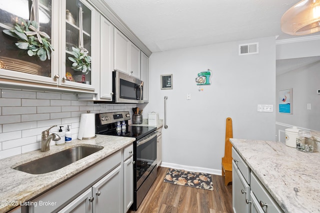 kitchen with visible vents, a sink, backsplash, dark wood-style floors, and stainless steel appliances