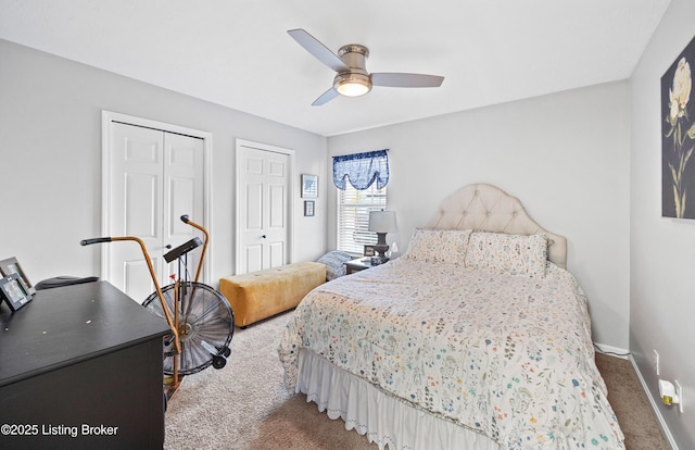 bedroom with carpet flooring, baseboards, multiple closets, and ceiling fan