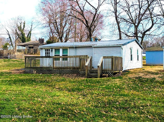 rear view of property featuring metal roof, an outbuilding, a lawn, and a deck