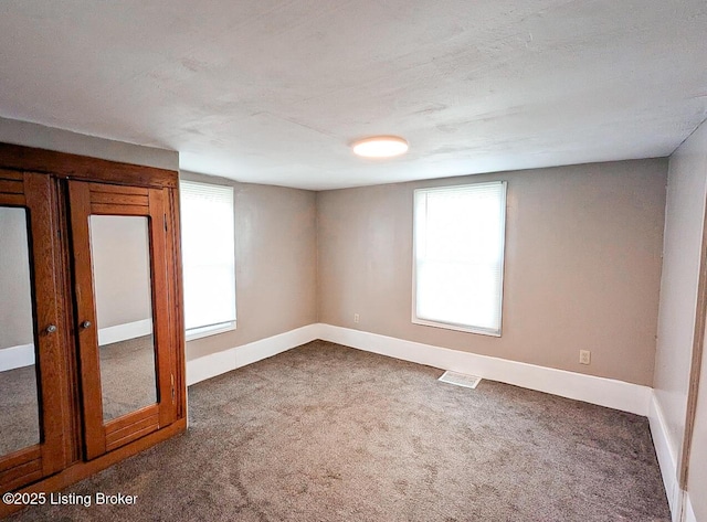 carpeted empty room with baseboards and visible vents