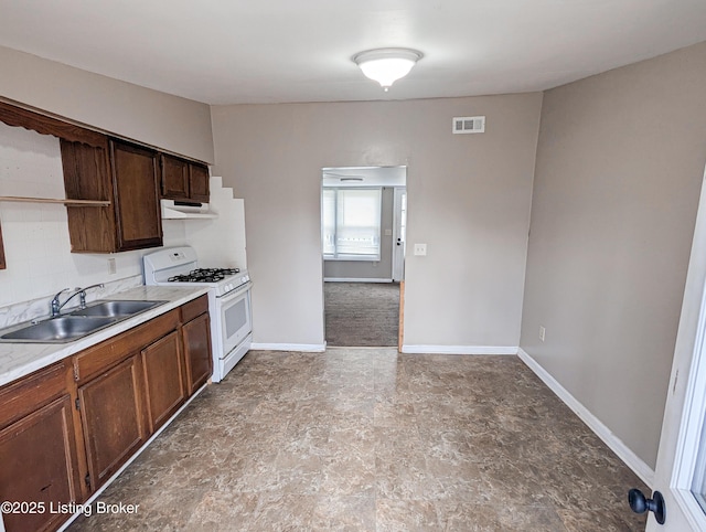 kitchen with visible vents, a sink, under cabinet range hood, baseboards, and white range with gas stovetop