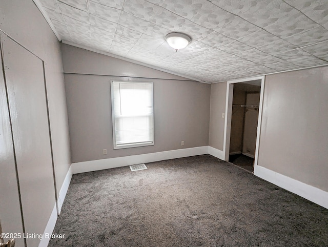 unfurnished bedroom with visible vents, baseboards, carpet, vaulted ceiling, and a closet