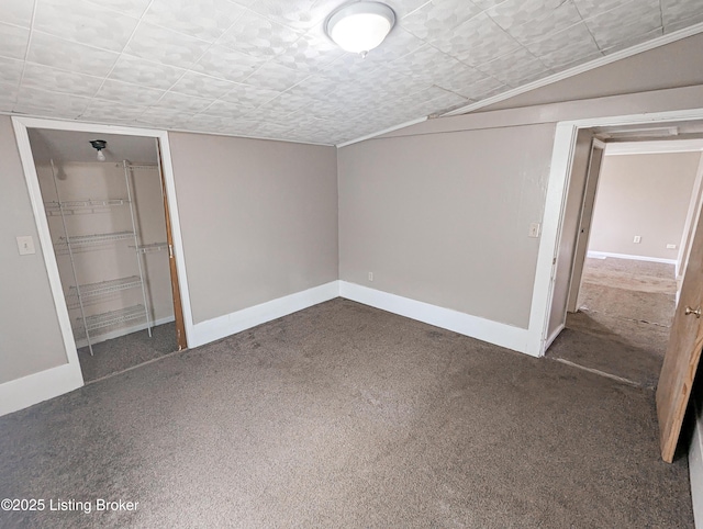 unfurnished bedroom with a closet, baseboards, carpet flooring, and vaulted ceiling