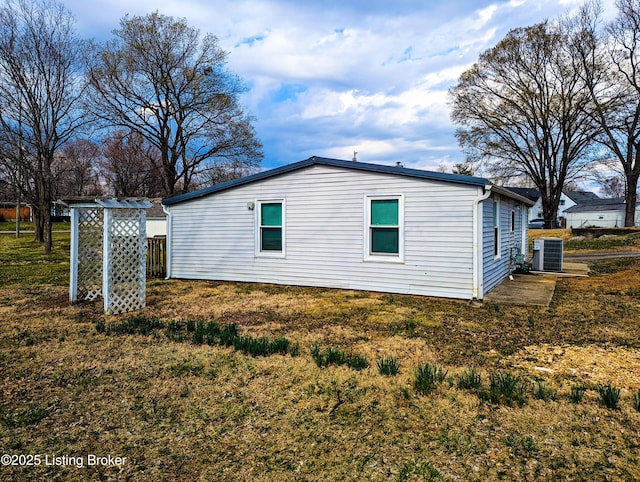 view of side of property featuring cooling unit and a yard