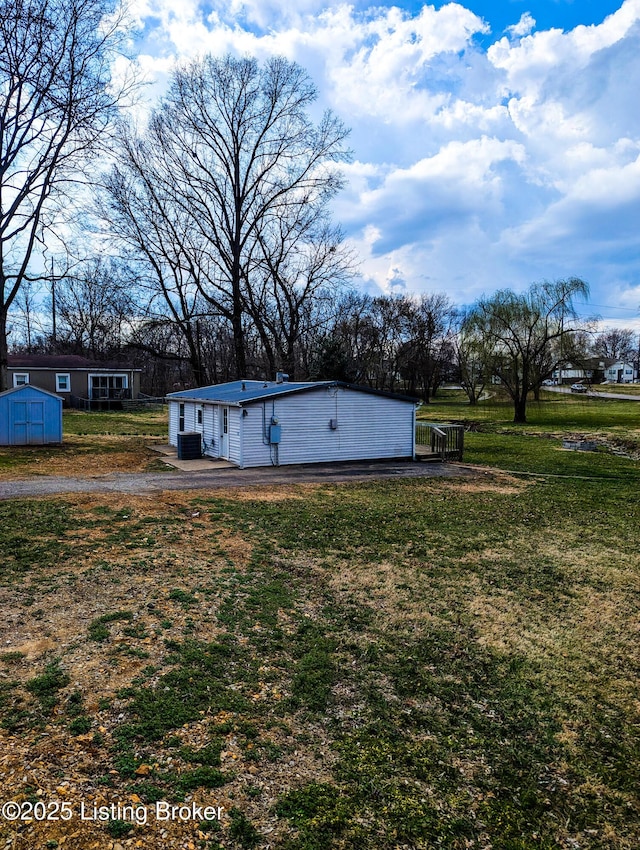 view of yard featuring a shed, central AC, and an outdoor structure