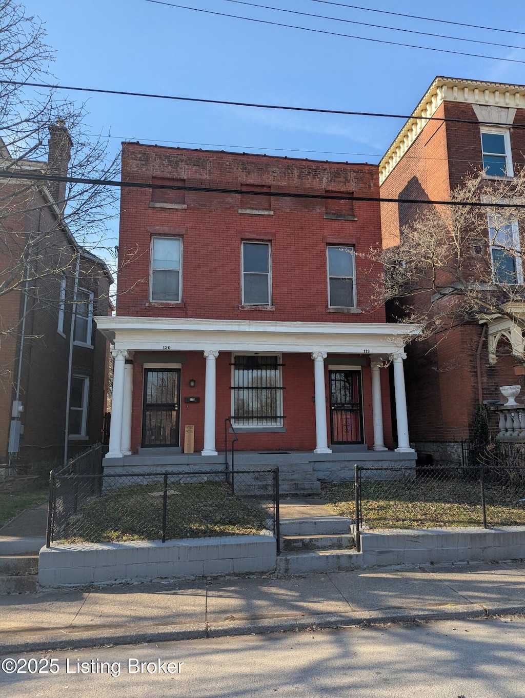 view of front of home with a fenced front yard, brick siding, and covered porch