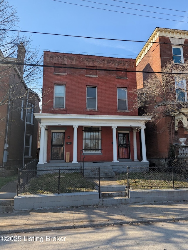 view of front of home with a fenced front yard, brick siding, and covered porch