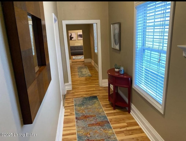 hall featuring baseboards and light wood-style flooring