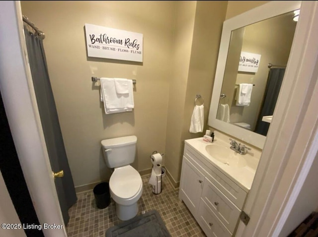 bathroom with baseboards, toilet, vanity, and tile patterned flooring