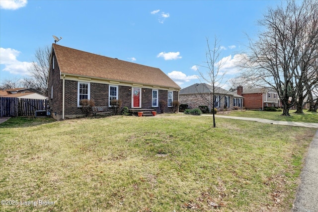 view of front of home featuring brick siding, roof with shingles, a front lawn, and fence