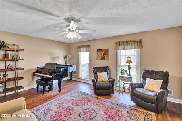 sitting room with a ceiling fan, wood finished floors, visible vents, and baseboards