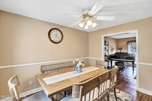 dining room with ceiling fan, a textured ceiling, baseboards, and dark wood-style flooring