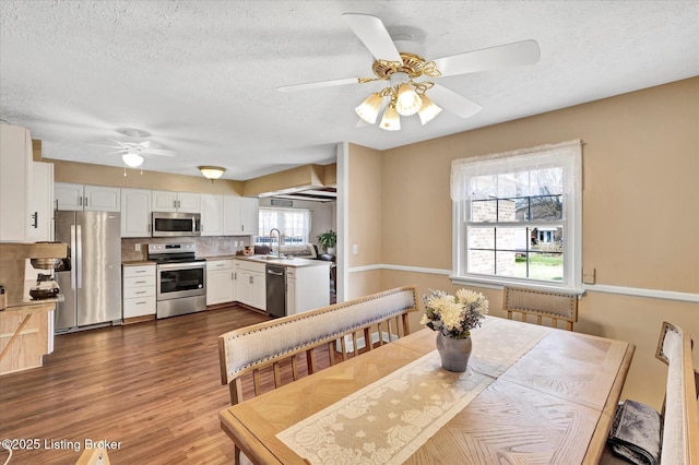 dining room with dark wood-type flooring, a ceiling fan, and a textured ceiling