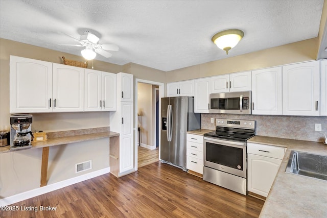 kitchen with visible vents, light countertops, stainless steel appliances, dark wood-style floors, and white cabinetry