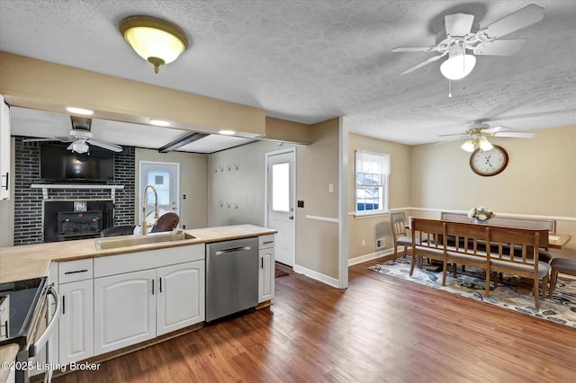 kitchen featuring a sink, a textured ceiling, wood finished floors, stainless steel appliances, and ceiling fan