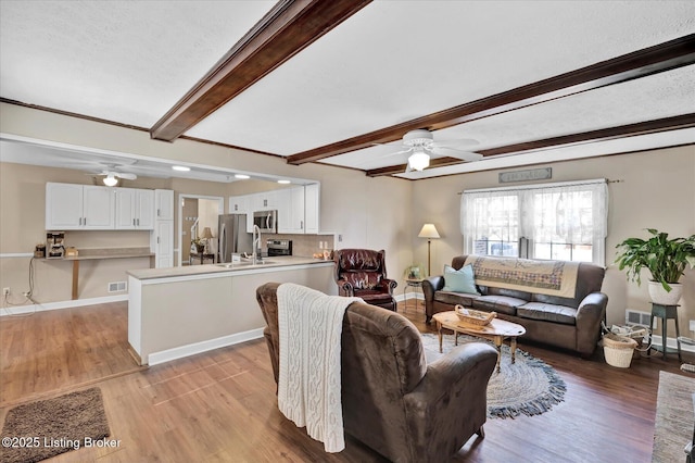 living room featuring light wood-type flooring, beam ceiling, baseboards, and ceiling fan