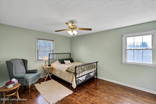 bedroom featuring baseboards, a textured ceiling, and wood finished floors