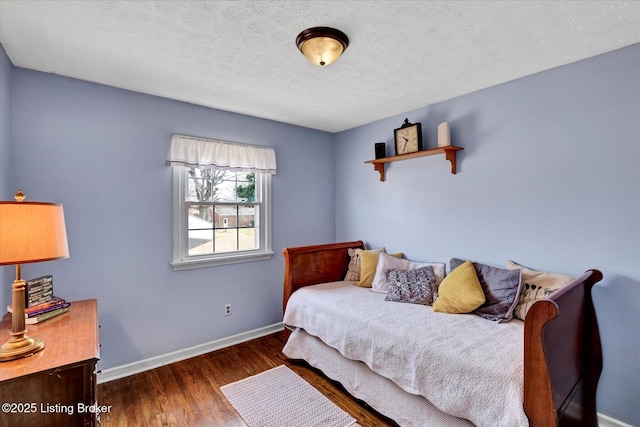 bedroom featuring a textured ceiling, baseboards, and wood finished floors