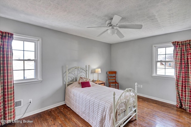 bedroom featuring visible vents, a textured ceiling, baseboards, and wood finished floors