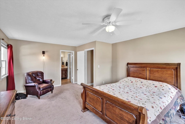 bedroom with a ceiling fan, baseboards, a textured ceiling, light carpet, and connected bathroom