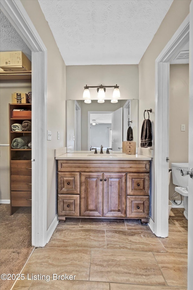 bathroom with vanity, toilet, visible vents, and a textured ceiling