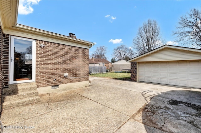 view of side of home with an outbuilding, fence, a chimney, a garage, and brick siding