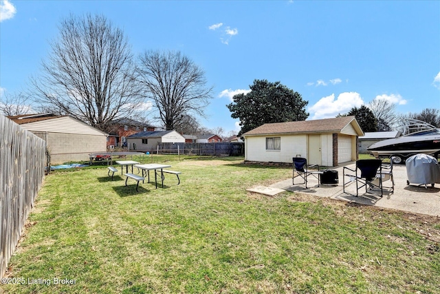 view of yard with a fenced backyard, a patio, a garage, and an outdoor structure