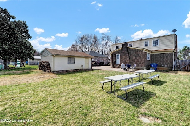 back of house with a yard, fence, brick siding, and entry steps