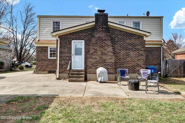 back of property with a patio area, entry steps, brick siding, and fence