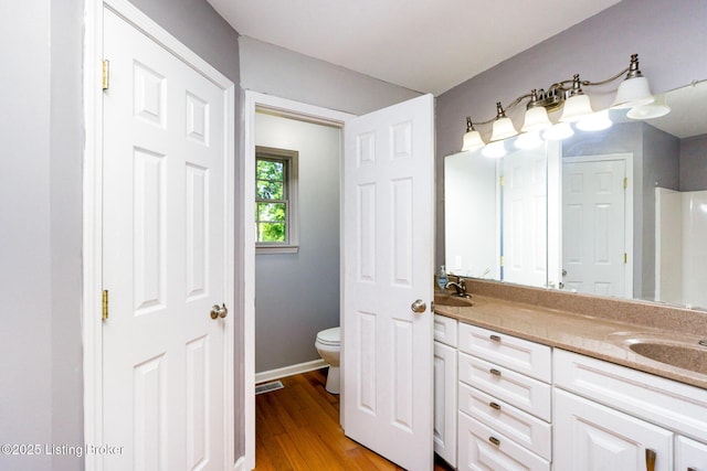 404 Persell Rd, Bedford, KY 40006 - bathroom featuring double vanity, toilet, wood finished floors, and baseboards