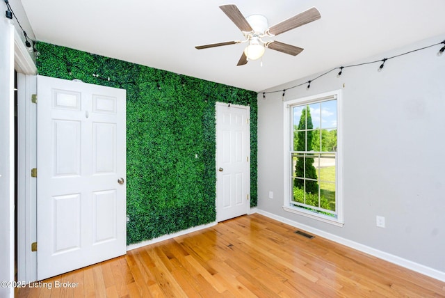 404 Persell Rd, Bedford, KY 40006 - unfurnished bedroom with baseboards, an accent wall, light wood-type flooring, and ceiling fan