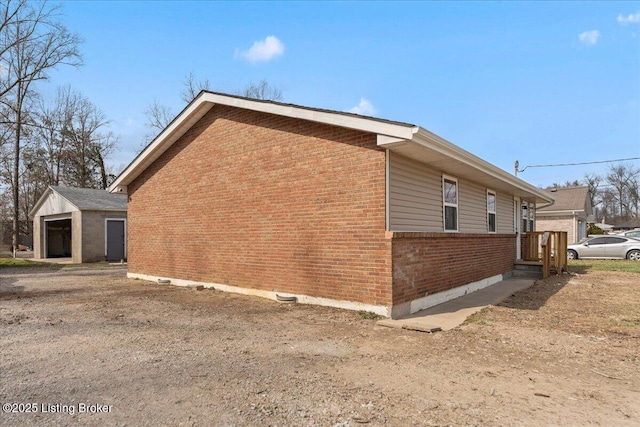 view of side of property featuring an outdoor structure, brick siding, and a detached garage