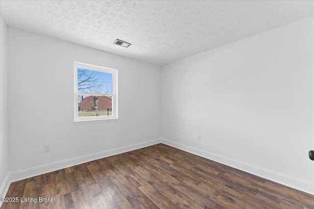 empty room featuring baseboards, visible vents, dark wood-style flooring, and a textured ceiling