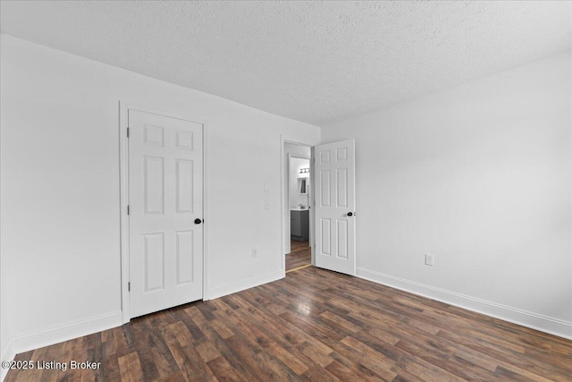 unfurnished bedroom featuring dark wood finished floors, a textured ceiling, and baseboards