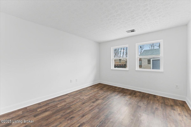 spare room with visible vents, baseboards, dark wood-style flooring, and a textured ceiling