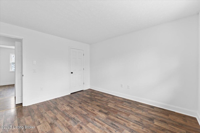 spare room featuring baseboards, a textured ceiling, and dark wood-style floors