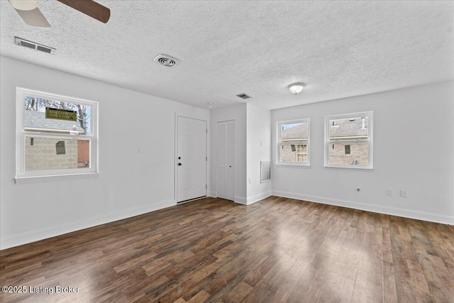 empty room with visible vents, dark wood finished floors, and a ceiling fan